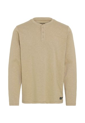 Bež majica s dugim rukavima henley kroja, izdelana iz mehkega materiala, z okroglim izrezom, tremi gumbi in majhno oznako na robu.