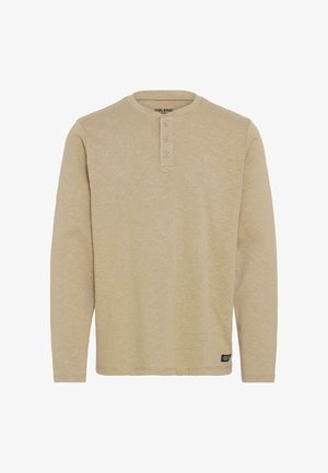 Beige langermet henley-skjorte laget av mykt materiale, med rund hals, tre knapper og en liten logo-merke ved kanten.