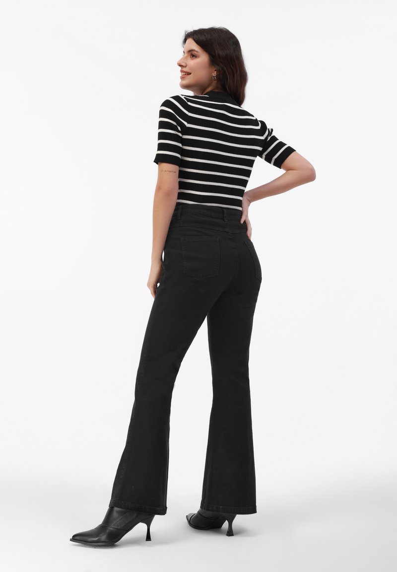 Czarne rozszerzane dżinsy zestawione z dopasowaną czarno-białą bluzką z krótkim rękawem w paski. Strój wyróżnia się gładką fakturą i elegancką sylwetką.