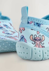 Niebieskie buty wsuwane z nadrukiem postaci Stitcza, miękka górna część z tkaniny, teksturowana jasnoniebieska gumowa podeszwa i wzmocniony uchwyt z tyłu dla łatwego zakładania.