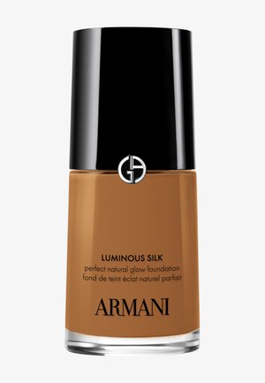 Fond de teint Luminous Silk dans un flacon en verre avec un bouchon noir mat. Liquide couleur bronzée avec texte noir et argenté. Base brillante et bords arrondis.