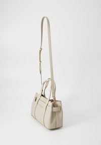Sac à main en cuir beige avec deux poignées supérieures et une bandoulière amovible, présentant une forme structurée et des détails de couture subtils.