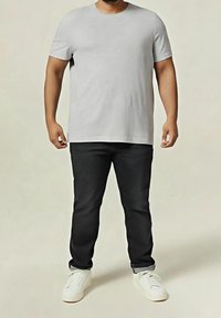 Graues T-Shirt mit kurzen Ärmeln kombiniert mit schwarzer Hose und weißen Turnschuhen. Das Shirt hat einen Rundhalsausschnitt, und das Outfit zeichnet sich durch eine lockere Passform aus.