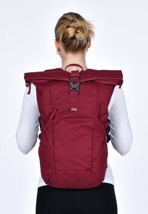 Rucksack aus rotem Stoff mit Rollverschluss und verstellbaren Trägern. Ausgestattet mit einer schwarzen Schnalle und Seitentaschen, entworfen für Funktionalität und Komfort.