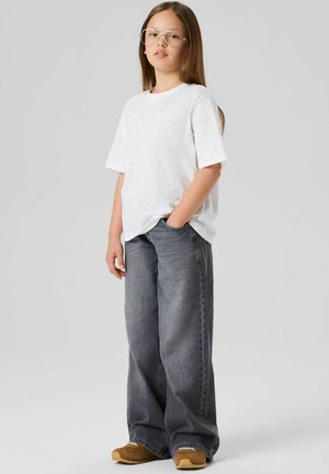 Witte korte mouwen shirt met kleine meerkleurige stippen, gecombineerd met losse grijze denim jeans. Bruine schoenen maken de outfit compleet.