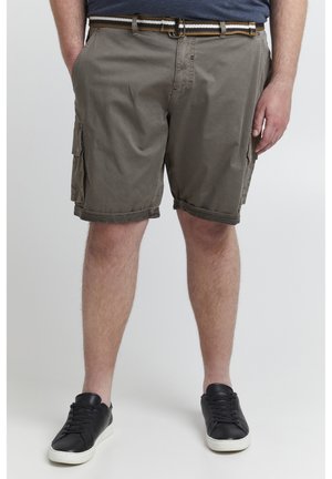 Khaki cargo shorts med lav midje, med sidelommer, rullekanter og et mønstret belte. Bært med svarte joggesko.