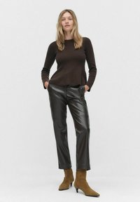 Bordeaux ribbeltrui, zwarte nep leren broek en tan enkellaarsjes met puntige neuzen. Eenvoudig ontwerp met een relaxte pasvorm.