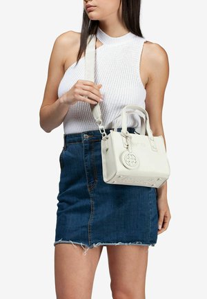 Bolso de piel blanca con asas cortas y una correa desmontable, que presenta un logo circular y un detalle en relieve en la parte frontal.