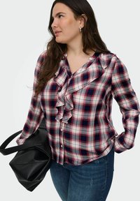 Blusa a quadri rossi e blu con scollatura arricciata, maniche lunghe e chiusura con bottoni, abbinata a una borsa tote nera in pelle.