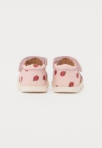 Rosa sko med marihøne mønster, med borrelåsrem og en teksturert rosa ankelkrage. Gummisåler og glatt syntetisk materiale.