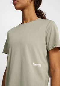 Ljusgrön kortärmad t-shirt med ribbad textur. Har en vit "hummel"-logotyp på vänster sida. Klassisk rundad halsdesign.