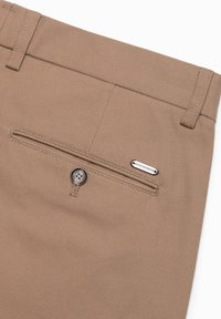 Pantalons beiges en tissu texturé, avec une poche arrière à fermeture bouton et un accent de marque métallique.