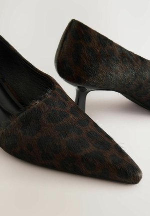 Czółenka na wysokim obcasie z wąskim noskiem, wykonane z ciemnobrązowego materiału w wzór zwierzęcy o miękkiej teksturze oraz czarnych obcasach typu stiletto. Subtelny połysk i czarne detale.
