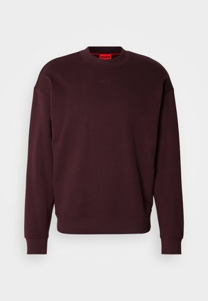 Vinröd sweatshirt i mjukt tyg, med rund halsringning, ribbade muddar och en liten präglad logotyp på bröstet.