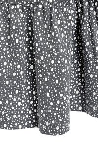 Šedá látka s bílým puntíkovým vzorem, s nabíraným designem a lemem, který končí těsně pod kolenem.