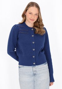 Cardigan lavorato a maglia blu con bottoni a forma di cuore, polsini a coste e decorazioni in perline sulle spalle. Texture morbida, design aderente.