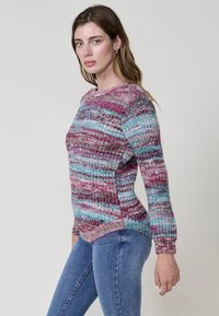 Suéter de punto multicolor con rayas horizontales en rosa, azul y beige. Cuello redondo con puños acanalados y aberturas laterales.