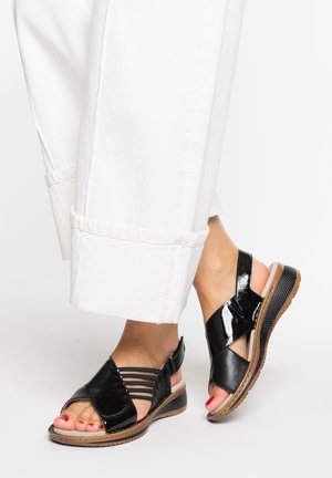 Black leather sandals with cross-straps, a textured sole, and a low heel. The design features an open toe and a polished finish.