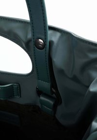 Borsa a tracolla verde con finitura lucida, dotata di manico in pelle e chiusura a scatto. L'interno presenta una fodera scura con dettagli minimali.
