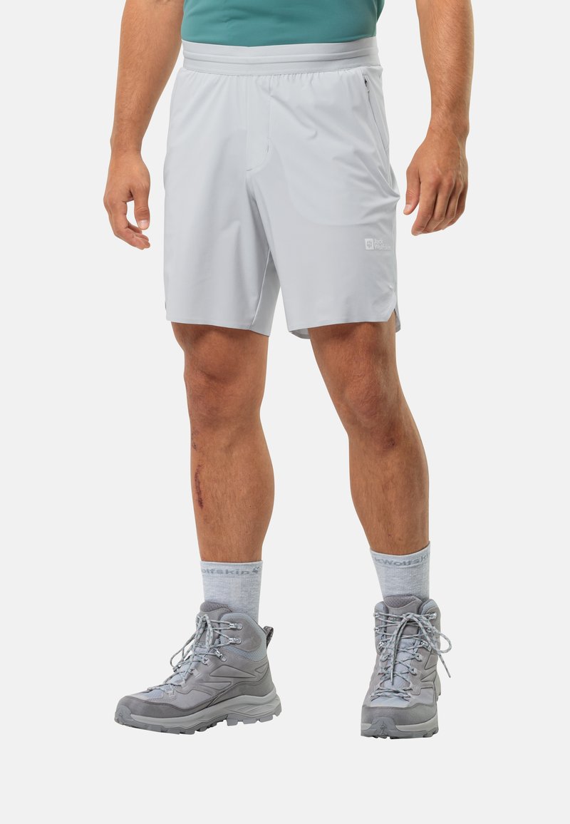 Helle graue Shorts mit elastischem Bund und einer Seitentasche, kombiniert mit grauen Wanderstiefeln und hellgrauen Crew-Socken.