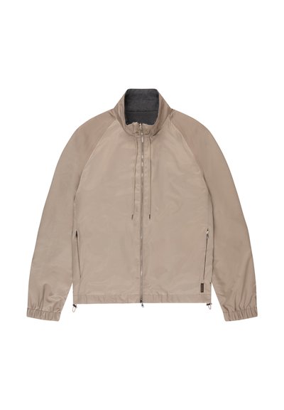 Giacca leggera beige con cerniera frontale, collo alto, coulisse, tasche laterali con cerniera e polsini elasticizzati, distesa su sfondo bianco.