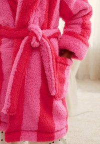 Fuzzy pink bathrobe with darker pink stripes, belted at the waist, featuring two front pockets and soft texture.