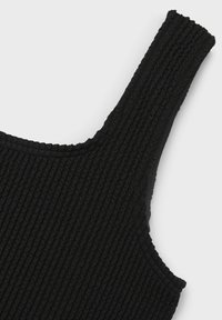 Top nero a coste con spalline spesse, tessuto testurizzato e scollatura curvata. Il materiale appare morbido ed elastico.