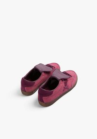 Pink suede kengät, joissa on pehmeä rakenne, violetti nahkavyö, pyöreä kärki ja ruskea kumipohja. Minimalistinen muotoilu, ei näkyvää brändäystä.