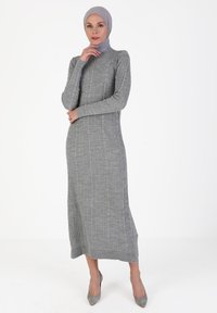 Gray ribbed dress with long sleeves and a high neckline, made from textured knit fabric. Floor-length with a fitted silhouette.