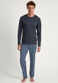 Chemise à manches longues bleu marine associée à un pantalon de pyjama à motifs bleus avec un design géométrique ; tissu doux, silhouette ajustée.