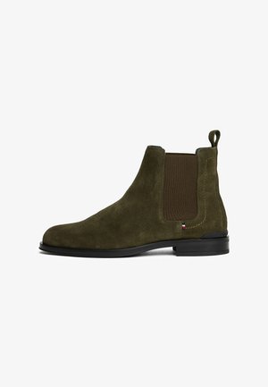 Olivengrüne Wildleder Chelsea-Boots mit elastischem Seitenpanel, Zuglasche an der Ferse, schwarzer Sohle und kleinem dreifarbigen Stoffetikett an der Seite.