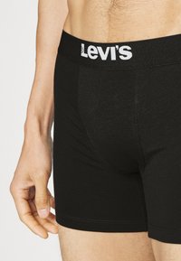Svarte bomullsmiks boksershorts med en hvit Levi's-logo på midjebåndet, med en glatt tekstur og tettsittende design.
