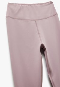 Leggings de tiro alto en color lavanda, confeccionadas con una tela elástica y costuras planas. Cuentan con una cinturilla suave y una forma ajustada alrededor de las piernas.