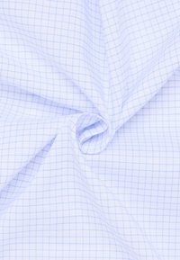 Tessuto bianco con motivo a griglia azzurro chiaro, attorcigliato liberamente al centro, mostrando texture e pieghe.