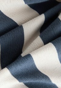Gestreepte stof met brede marineblauwe en crème banden. Zachte textuur met geweven details, die diepte en contrast in kleur creëren.