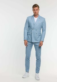 Hellblauern, doppelt geknöpften Anzug mit passenden, slim-fit Hosen. Maßgeschneiderte Optik mit subtiler Textur und weißen Sneakers.