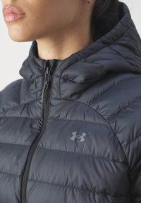 Schwarze Daunenjacke mit Kapuze, featuring horizontale Nähte, einen vorderen Reißverschluss und ein kleines graues Logo auf der Brust. Glatte Textur.