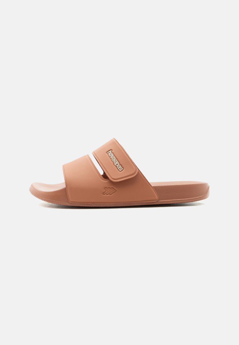 Sandale mule simple couleur sable avec bride ajustable et logo "havaianas" sur le côté, vue de profil sur fond blanc.
