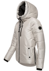 Puffjacka i ljus beige, med huva, svart dragkedja och knappar. Designen inkluderar quiltad textur och ribbade manschetter för värme.