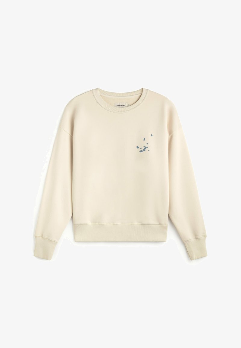 Sweat-shirt crème à col rond avec manches longues et petit motif dispersé de points bleus sur le côté gauche de la poitrine.