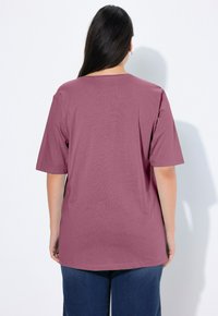 T-shirt a maniche corte, dalla vestibilità rilassata, in tessuto mauve. Presenta un colletto rotondo, una texture liscia e cuciture laterali, abbinato a pantaloni in denim.