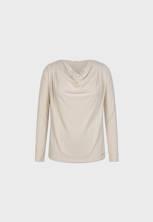Dlouhý rukáv, krémový top s drapovaným výstřihem, hladkým materiálem a decentním nařasením na ramenou.
