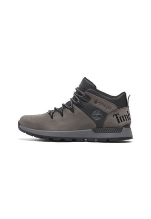 Botte de randonnée Timberland Gore-Tex mi-haute grise et noire avec lacets à l'avant, semelle robuste, patch logo sur le côté et languette arrière.
