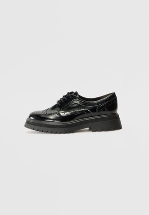 Scarpe oxford in pelle verniciata nera con dettagli brogue, suola bassa e spessa, e punta rotonda. Presentano chiusura con lacci e accentuazioni testurizzate.
