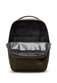 Zeleni platneni ruksak sa zatvaranjem na patentni zatvarač, koji ima prostrano crno unutrašnjost i srebrnu mrežastu torbicu za organizaciju.
