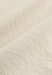 Tissu beige avec une surface douce et texturée, présentant des ondulations subtiles et un aspect naturel, sans imperfections. Idéal pour diverses applications textiles.