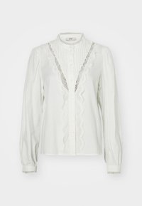 Blouse blanche avec des manches froncées, des plis verticaux et une dentelle le long de la patte de boutonnage. Dotée d'une fermeture à boutons et de poignets décoratifs.