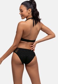 Juodas bikini kostiumėlis, turintis tekstūruotą nėrinių raštą, kaklo ryšio dizainą ir aukštu liemeniu su išpjovomis.