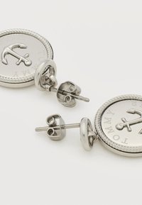 Ασημένια καρφωτά σκουλαρίκια με στρογγυλούς μενταγιόν που απεικονίζουν ανάγλυφη άγκυρα και τη λέξη "Tommy" σε λευκό φόντο.