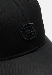 Cappello nero in cotone con una texture liscia, caratterizzato da un logo ricamato sulla parte frontale. Design strutturato con una visiera curva.